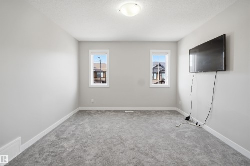 Carpeted interior space featuring light gray walls, two windows with white trim, and a ceiling-mounted light fixture - 1234 Daniels Crescent, Edmonton, AB - Indoor Photo Showing Other Room