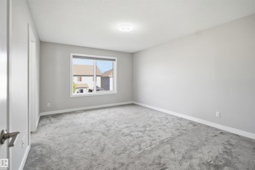 Spacious room featuring light gray walls, gray carpet, a single window, white trim, and a flush-mount ceiling light - 1234 Daniels Crescent, Edmonton, AB - Indoor Photo Showing Other Room