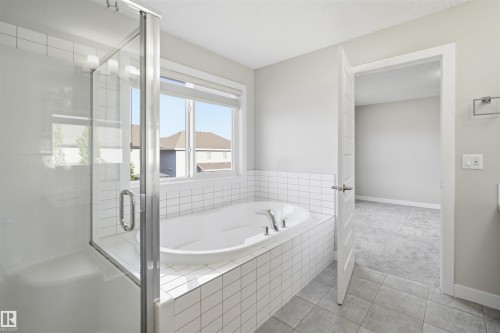 Contemporary bathroom with an oversized soaking tub, glass-enclosed shower, white subway tile surround, and light gray floor tiling - 1234 Daniels Crescent, Edmonton, AB - Indoor Photo Showing Bathroom