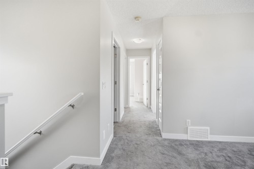 Interior hallway featuring light gray walls, gray carpet flooring, white baseboards, and white doors - 1234 Daniels Crescent, Edmonton, AB - Indoor Photo Showing Other Room