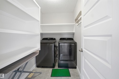 Dedicated laundry area featuring white shelving, tile flooring, and a modern paneled door - 1234 Daniels Crescent, Edmonton, AB - Indoor Photo Showing Laundry Room