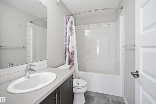 Full bathroom featuring a vanity with an integrated sink, dark wood-finish cabinetry, and a contemporary faucet - 1234 Daniels Crescent, Edmonton, AB - Indoor Photo Showing Bathroom