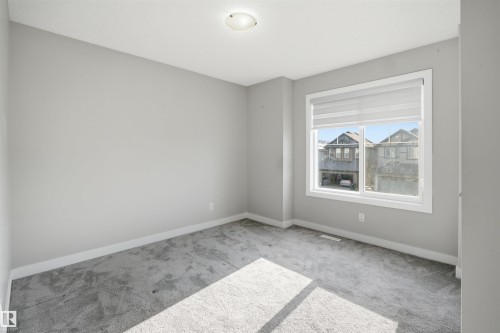 Neutral-toned room featuring a large window with privacy blinds, light gray carpet, and white trim - 1234 Daniels Crescent, Edmonton, AB - Indoor Photo Showing Other Room