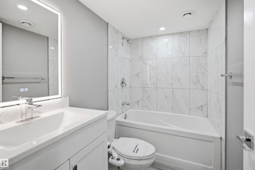 Full bathroom featuring a white vanity with integrated sink, chrome faucet, and an illuminated mirror - 1234 Daniels Crescent, Edmonton, AB - Indoor Photo Showing Bathroom