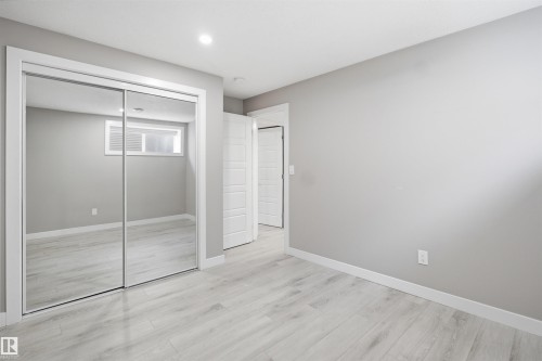 Spacious room featuring mirrored closet doors, recessed lighting, light-toned wood-finish flooring, and crisp white trim - 1234 Daniels Crescent, Edmonton, AB - Indoor Photo Showing Other Room