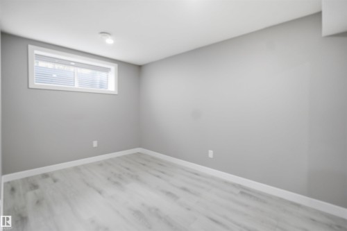 Light gray wood-finish flooring complements the matching wall color and white baseboards - 1234 Daniels Crescent, Edmonton, AB - Indoor Photo Showing Other Room