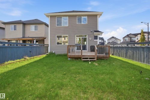 Expansive green lawn featuring a wooden deck with railing, a two-story exterior with horizontal siding, and multiple windows - 1234 Daniels Crescent, Edmonton, AB - Outdoor With Backyard
