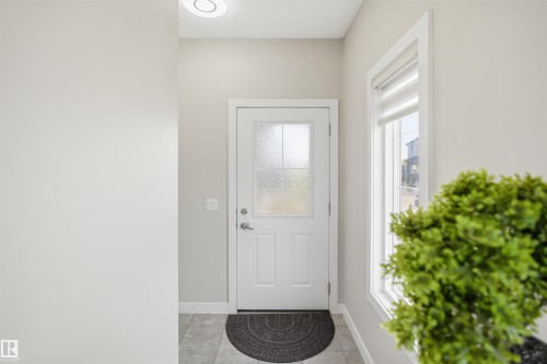 Entryway featuring a white door with frosted glass panels, a full-length side window with a roller shade, and light gray tile flooring - 1234 Daniels Crescent, Edmonton, AB - Indoor Photo Showing Other Room