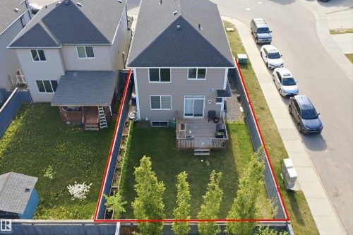 Rear exterior featuring a ground-level deck, sliding patio door, and mature trees - 1234 Daniels Crescent, Edmonton, AB - 