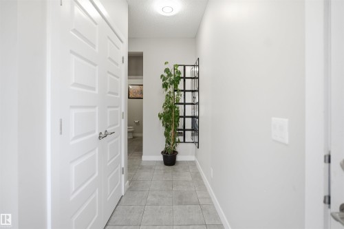 Hallway with light gray tile flooring, white baseboards, and a flush-mount ceiling light fixture - 1234 Daniels Crescent, Edmonton, AB - Indoor Photo Showing Other Room