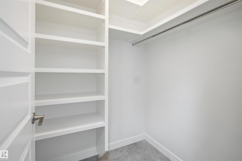 Built-in closet system featuring white shelving, a full-width hanging rod, and grey tile flooring - 1234 Daniels Crescent, Edmonton, AB - Indoor With Storage