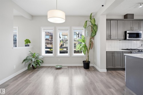Bright living area featuring wood-finish flooring, a contemporary drum pendant light, and three windows providing natural illumination - 1234 Daniels Crescent, Edmonton, AB - Indoor Photo Showing Kitchen