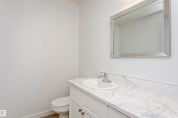 Vanity area featuring a white cabinet with brushed nickel hardware, a white countertop with grey veining, an undermount sink, and a chrome faucet - 
