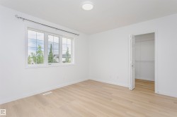 Bright room featuring light wood-finish flooring and a large window with gridded panes - 