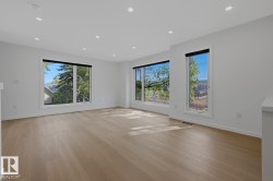 Bright interior space featuring light wood-finish flooring, white walls, and multiple large windows with black roller shades - 