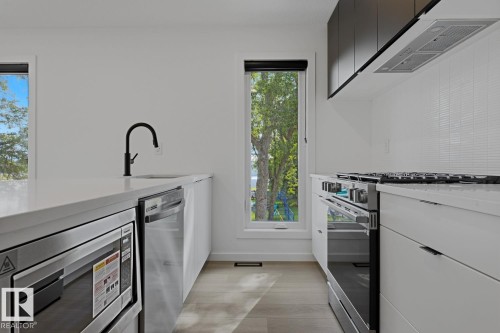 Modern kitchen featuring white cabinetry, light wood-finish flooring, and white countertops - 8903 94 Ave Nw, Edmonton, AB 