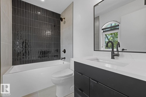 Bathroom featuring a built-in tub with dark vertical subway tile surround and matte black fixtures - 8903 94 Ave Nw, Edmonton, AB 