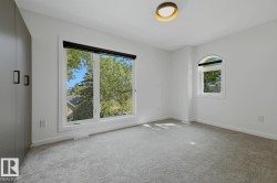 Bright room featuring a large picture window, an arched window, light gray carpeting, and a built-in wardrobe with modern pull handles - 
