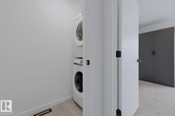 Dedicated laundry area featuring a stacked washer and dryer, light-toned flooring, and neutral wall finishes - 
