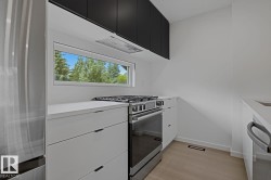 Modern kitchen featuring a stainless steel gas range, coordinating stainless steel refrigerator, white countertops, and a white tile backsplash - 