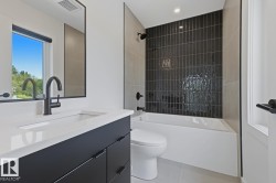 Contemporary bathroom featuring a black vanity with a white countertop, an undermount sink, and a matte black faucet - 