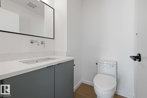 Modern bath featuring a wall-mounted faucet, rectangular undermount sink, quartz countertop, and dark gray cabinetry - 8903 94 Ave Nw, Edmonton, AB 