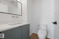 Modern bath featuring a wall-mounted faucet, rectangular undermount sink, quartz countertop, and dark gray cabinetry - 