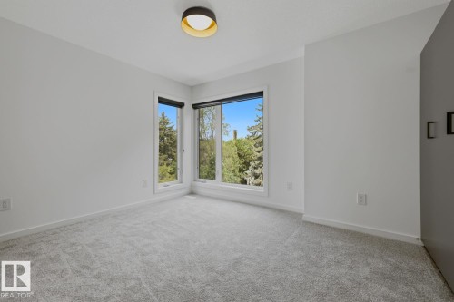 Bright room featuring a modern flush-mount ceiling light fixture, light gray carpeting, and white trim - 8903 94 Ave Nw, Edmonton, AB 