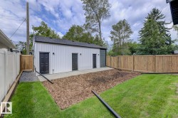 Detached structure with white vertical panel siding, dark shingle roof, and three dark entry doors - 
