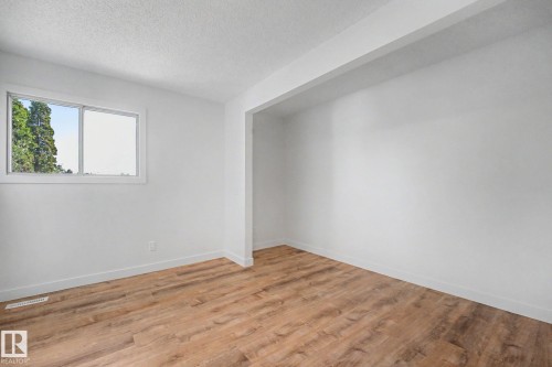 Bright interior space featuring wood-finish flooring, white baseboards, and a window with a white frame - 60 Mcnabb Crescent, Stony Plain, AB - Indoor Photo Showing Other Room
