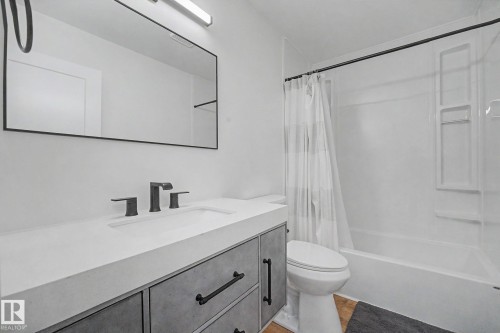 Contemporary bathroom featuring a vanity with a white countertop and integrated sink, matte black faucet, and a large black-framed mirror - 60 Mcnabb Crescent, Stony Plain, AB - Indoor Photo Showing Bathroom