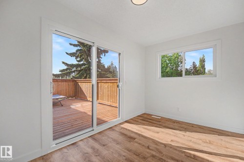 Spacious room featuring wood-finish flooring, a large window, and a sliding glass door providing direct access to an outdoor deck - 60 Mcnabb Crescent, Stony Plain, AB - Indoor Photo Showing Other Room