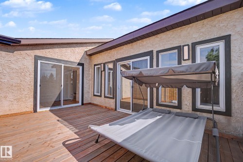 Expansive wood deck featuring multiple sliding glass doors and windows with dark trim, offering broad access to interior spaces - 60 Mcnabb Crescent, Stony Plain, AB - Outdoor With Deck Patio Veranda With Exterior