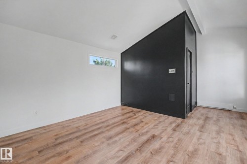 Spacious room featuring wood-finish flooring, white walls, and a contrasting black accent wall - 60 Mcnabb Crescent, Stony Plain, AB - Indoor Photo Showing Other Room
