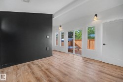Spacious interior room featuring wood-finish flooring, a prominent black accent wall, and recessed ceiling lighting - 