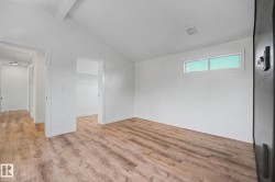 Room featuring wood-finish flooring, vaulted ceiling, and a high horizontal window - 
