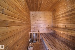 Wood-paneled sauna featuring a multi-tiered bench, slatted wood flooring, and a built-in heater - 