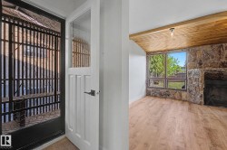 Entryway featuring a white paneled door with glass insert, black security door, and wood-finish flooring - 