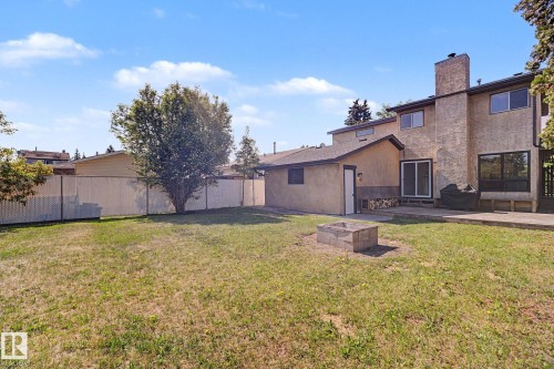 Expansive backyard featuring a central fire pit, concrete patio, and mature tree - 60 Mcnabb Crescent, Stony Plain, AB - Outdoor