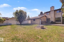 Expansive backyard featuring a central fire pit, concrete patio, and mature tree - 