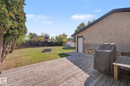Expansive outdoor deck area with wood-finish decking, directly beside a stucco-finish exterior wall featuring a functional door - 60 Mcnabb Crescent, Stony Plain, AB - Outdoor With Deck Patio Veranda