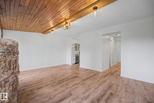 Open concept living area featuring wood-finish flooring, a wood plank ceiling, and a stone-clad fireplace - 60 Mcnabb Crescent, Stony Plain, AB - Indoor Photo Showing Other Room