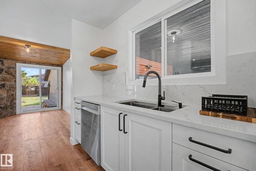 Modern kitchen featuring white shaker cabinetry with matte black hardware, stone-finish countertops, and a stainless steel dishwasher - 60 Mcnabb Crescent, Stony Plain, AB - Indoor Photo Showing Kitchen With Double Sink