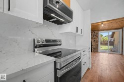 Kitchen featuring white shaker-style cabinetry with matte black hardware, stainless steel appliances, and a white countertop with a matching backsplash - 
