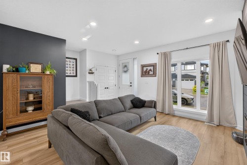 Open concept living area featuring light wood-finish flooring, recessed ceiling lighting, and a prominent large window with white trim - 548 Kleins Crescent, Leduc, AB 