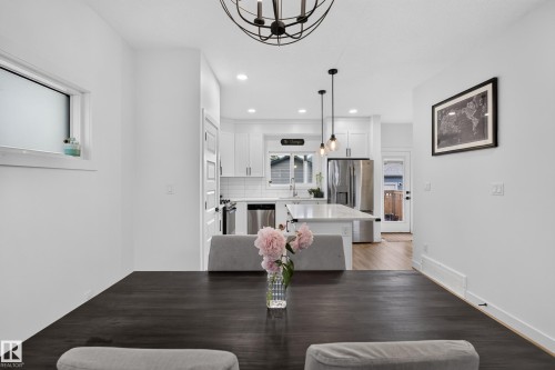 Modern open-concept living space featuring a dark wood-finish dining table - 548 Kleins Crescent, Leduc, AB 