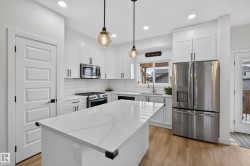 Modern kitchen featuring a white quartz-finish island with seating space - 