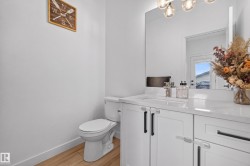 Bathroom featuring white cabinetry, a rectangular sink, polished chrome fixtures, and wood-finish flooring - 