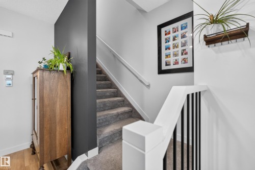 Stairwell featuring carpeted steps, white handrails, and black vertical balusters - 548 Kleins Crescent, Leduc, AB 