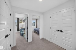 Hallway featuring light gray carpet flooring, white walls, and five-panel interior doors with matte black hardware - 